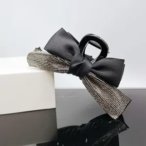 Detail of elegant black ribbon hair claw clip featuring sparkling rhinestone embellishments