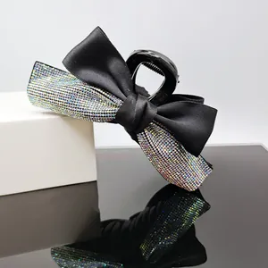 Detail of elegant black silk bow hair claw clip with colorful rhinestones on dark base