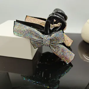 Detailed view of black hair claw clip with large iridescent rhinestone bow and strong spring