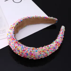 Close-up of padded headband with colorful glitter sprinkles on black mirror background
