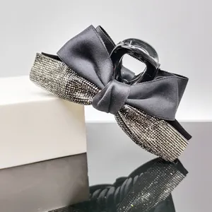 Close-up of elegant black satin ribbon hair claw clip with shimmering silver rhinestones
