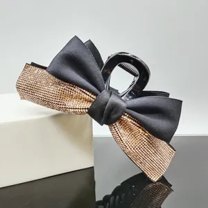 Detail of elegant black ribbon bow hair claw clip with sparkling champagne rhinestones