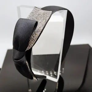 Dettaglio di un cerchietto in raso nero con grande fiocco e strass argentati scintillanti