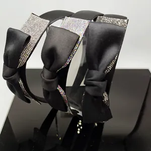 Dettaglio di tre cerchietti in raso nero con fiocchi decorati con cristalli lucidi
