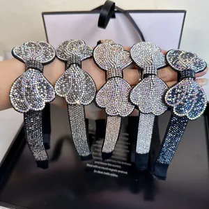 Close-up of five rhinestone bow headbands in various colors held by hand