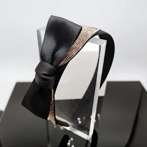 Dettaglio del cerchietto in raso nero con fiocco grande e strass brillanti