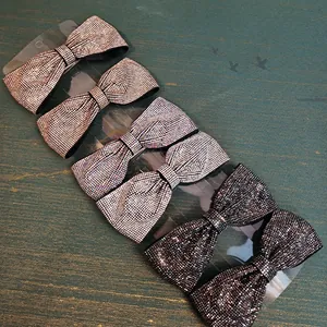 Vue détaillée des barrettes nœud en strass en couleurs doré champagne, argent et noir