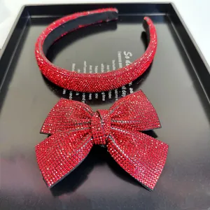 Détail du serre-tête en strass rouges et pince à cheveux nœud sur un plateau