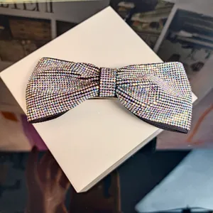 Gros plan d'une barrette nœud en cristaux AB étincelants sur un élégant boîtier blanc