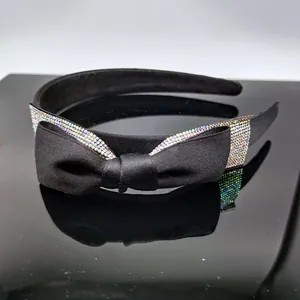 Dettaglio macro della fascia in tessuto nero con strass colorati e fiocco scintillante