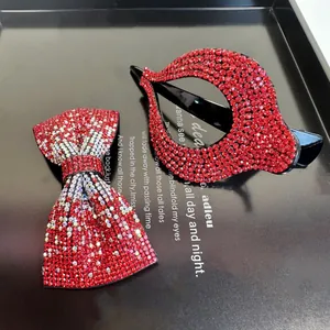 Détail d'un lot de barrettes à nœud rouge et strass brillants sur fond noir élégant