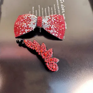 Détail de la pince à cheveux nœud rouge en strass et de la pince banane sur magazine