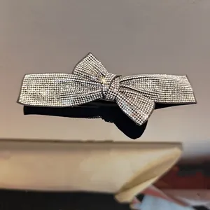 Macro shot of silver bow hair clip with sparkling rhinestones on reflective surface