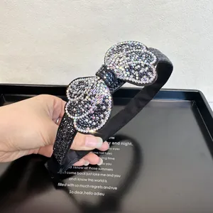 Close-up of elegant black headband featuring iridescent rhinestones on a big bow