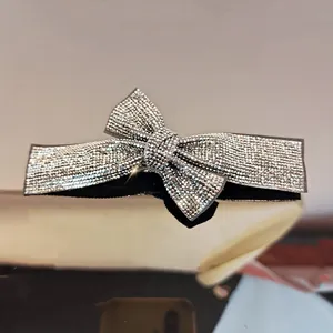 Macro shot of silver crystal bow hair clip with shimmering rhinestones on reflective surface
