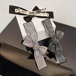 Detailed view of sparkling rhinestone bow hair clips and black fabric bow with metal spring clip