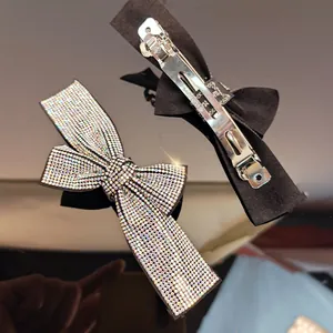 Detailed macro view of bow hair clip featuring sparkling rhinestones and metal spring mechanism