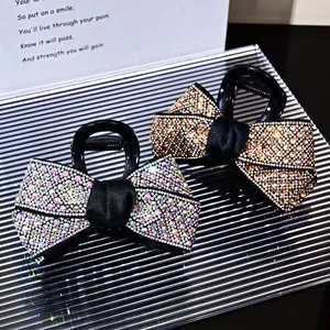 Elegant rhinestone bow hair claws in silver and champagne gold on a metallic tray