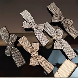 Sparkling rhinestone bow hair clips in assorted colors on a glossy black reflective background