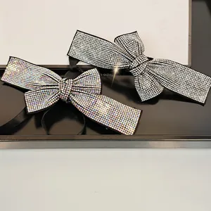 Detail view of crystal bow hair clips with shimmering rhinestones on black satin base