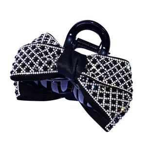 Elegant medium hair claw clip featuring a rhinestone bow design on a black glossy base