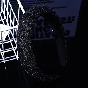 Gros plan d'un serre-tête rembourré de luxe avec strass noirs sur surface miroir