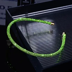 Detailed close-up of emerald green rhinestone headband on a black textured tray