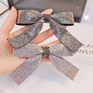 Détail des strass étincelants sur les pinces à cheveux en forme de nœud gris et blanc