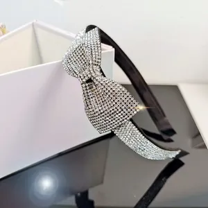 Close-up of elegant bow headband with sparkling rhinestones on a black satin frame