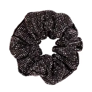 Close-up of black fabric scrunchie with sparkling rhinestones on a white background