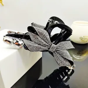 Detail of black hair claw clip with large silver rhinestone bow and crystal accents