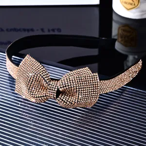 Detailed close-up of sparkling champagne rhinestone bow on a black velvet headband