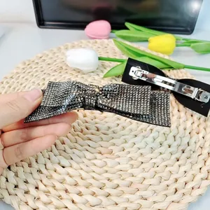 Détail de la barrette à cheveux nœud noir avec strass scintillants et pince en métal