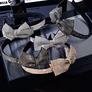 Sparkling crystal bow headbands in silver and gold displayed on a dark luxury tray