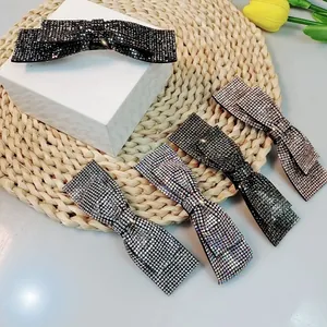 Barrettes nœud en strass déclinées en cinq couleurs sur un fond crème élégant et épuré