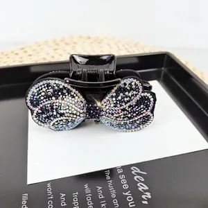 Elegant bow-shaped hair claw clip with colorful rhinestones on a stylish black finish