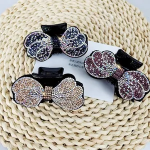 Close-up of three premium rhinestone bow hair claws in purple, gold, and wine red