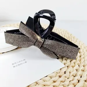 Detail of a large black hair claw clip with a sparkling rhinestone bow design