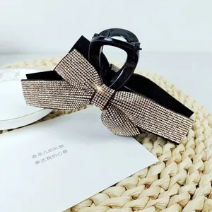 Close-up of a large black hair claw clip featuring a sparkling rhinestone-studded bow