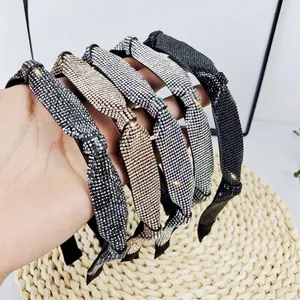 Détail de cinq serre-têtes étincelants en strass de différentes couleurs sur tapis