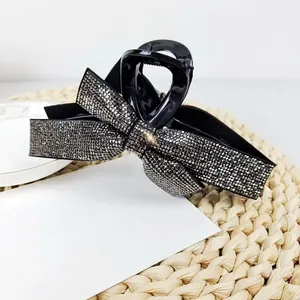 Detailed view of large black shark clip featuring a sparkling rhinestone bow design