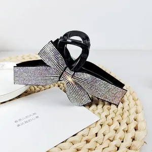 Detail view of large black hair claw clip with sparkling rhinestones in bow design