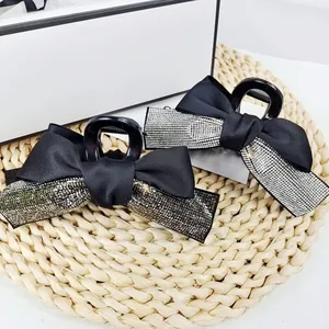 Détail montrant d'élégantes pinces à cheveux en satin noir avec strass argentés brillants