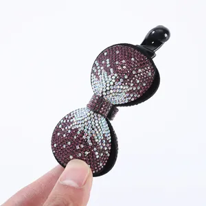 Detalle de una pinza de pelo tipo banana con lazo de diamantes morados sujeta a mano