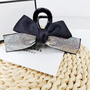 Détail de la pince à cheveux vintage avec nœud en satin noir et strass multicolores