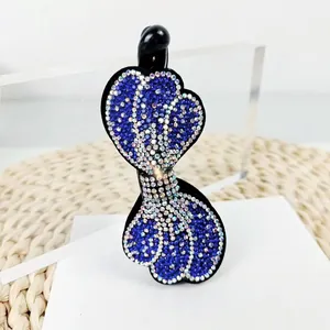 Detalle de diamantes de imitación azules y blancos en forma de corazón en un clip banana