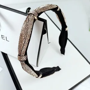 Detail of a black knotted headband with sparkling champagne rhinestones on white backdrop