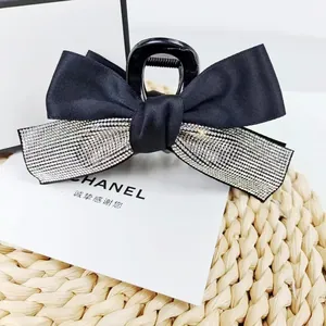 Détail de pince à cheveux vintage à nœud en satin noir avec des strass scintillants