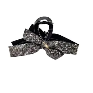 Detail shot of a large black bow hair claw clip with shimmering rhinestones and metal spring