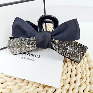 Détail d'une élégante pince à cheveux noire à double nœud avec décoration en strass brillants